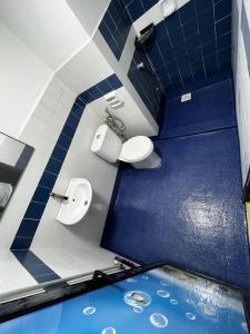 La salle de bains est pourvue de 2 toilettes et d'un mur bleu. dans l'établissement The EH's Homestay Marina View Villa PortDickson, à Port Dickson