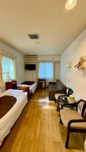 a room with two beds and a couch and a table at Pension Eastmountain Hakuba in Hakuba