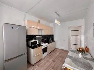 a kitchen with a refrigerator and a stove at Квартира рядом с Усолкой Сатпаева 348 in Pavlodar