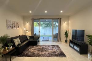 a living room with a black couch and a tv at Timeless Tranmere Escape By Host Solutions in Norwood