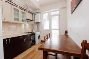 a kitchen with a wooden table and a dining room at Apartament confortabil Chișinău in Chişinău +6 photos