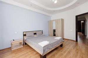 a white bedroom with a bed and a wooden floor at Apartament confortabil Chișinău in Chişinău