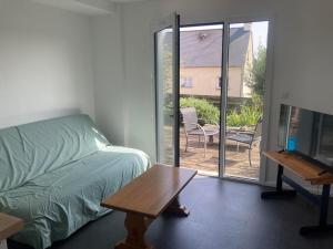 a bedroom with a bed and a table and a sliding glass door at accommodation for 4 people maximum in Guignen
