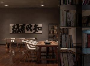 a dining room with a table and chairs and books at The Hermitage Hotel in Chengdu