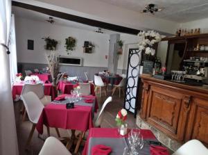 a dining room with pink tables and white chairs at La petite auberge 