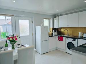 a kitchen with a white refrigerator and a table with chairs at Fully accessible bungalow by the Beach in Port Talbot