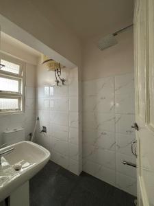 a white bathroom with a sink and a shower at Kerphida B&B in Shillong