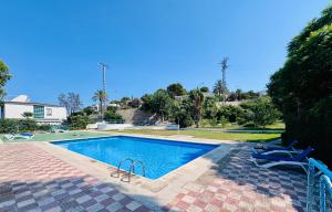 a swimming pool with two blue chairs next to it at Leo Apartamentos La Cova in Peniscola
