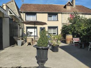 a house with an umbrella and plants in a courtyard at Appartement Parking Wifi Terrasse cosy in Condé-sur-Sarthe