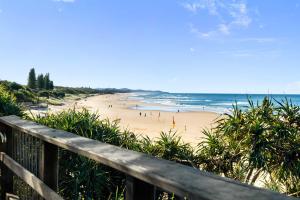 a beach with people on the sand and the ocean at The Palms in Coolum Beach - Unit A in Coolum Beach