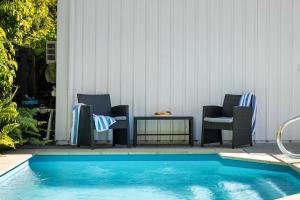 a swimming pool with chairs and a table next to it at The Palms in Coolum Beach - Unit B in Coolum Beach +29 photos
