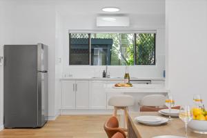a kitchen with a refrigerator and a table with chairs at The Palms in Coolum Beach - Unit B in Coolum Beach +29 photos