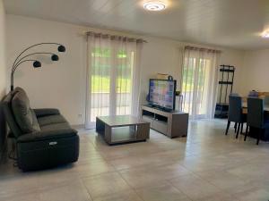 a living room with a tv and a couch and a table at Le Plain-pied du Pêcheur - Maison avec terrasse entre Loire, Via Velay et Le Puy in Brives-Charensac +16 photos