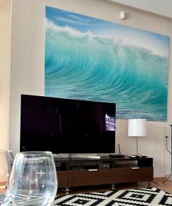 バラトンセメッシュにあるRemora Apartman Balatonszemesの絵画が飾られたリビングルームの大型スクリーンテレビ