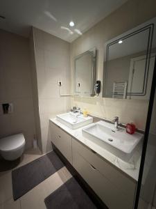 ein Badezimmer mit zwei Waschbecken und einer Toilette und einem Spiegel in der Unterkunft Belgrade Waterfront apartments in Belgrad