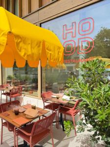 ein Restaurant mit Tischen und Stühlen und einem gelben Sonnenschirm in der Unterkunft HOOD Hotel in Genf + 28 Fotos
