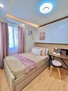 a bedroom with a bed and a desk with a chair at Adi Hideaway Staycation at Arezzo Place Davao in Davao City