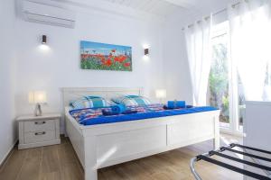 a bedroom with a white bed with a blue comforter at Steinhaus Mediterra mit Pool & Meerblick - Lukoran, Insel Ugljan bei Zadar in Lukoran +63 photos