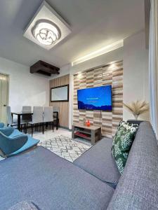a living room with a couch and a flat screen tv at Adi Hideaway Staycation at Camella Northpoint 2 Bedroom in Davao City