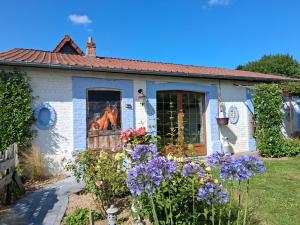 Une petite maison blanche avec des fleurs dans la cour dans l'établissement le cottage, à Martin-Église