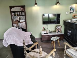 un salon avec une télévision, une chaise et une table dans l'établissement le cottage, à Martin-Église