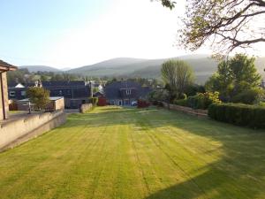 a large grassy yard with houses and mountains in the background at Inveravon Holiday Home in Dufftown