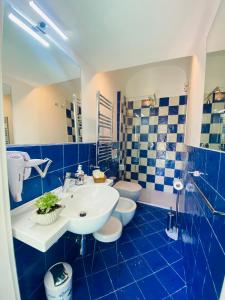 a blue tiled bathroom with a sink and two toilets at Antico Borgo in Minori