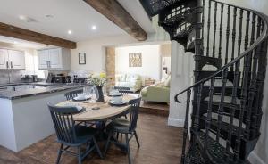 a kitchen and living room with a table and a spiral staircase at Blacksmiths in Brauncewell