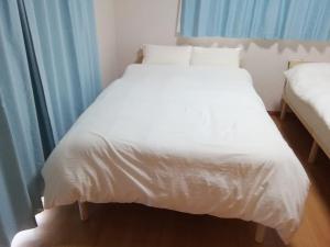 a large white bed in a room with blue curtains at ゲストハウスえらぶー7 in Wadomari +20 photos