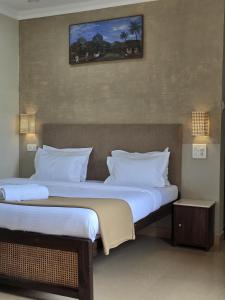 a bedroom with two beds with white pillows at Golden Pearl Beach Resort in Baga