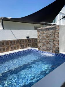 una gran piscina con una pared de ladrillo y azulejos azules en Le Cozy Home PRIVATE POOL MELAKA, en Melaka
