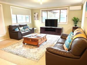 a living room with a couch and a coffee table at Tuncurry tranquility PID -STRA - 59456 in Tuncurry
