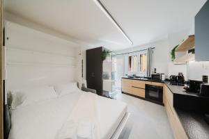 a white bedroom with a large bed and a kitchen at Borgo apartment - Vicino Centro in Belluno