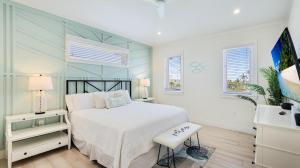 een slaapkamer met een wit bed en een stoel bij Oar House in Anna Maria +54 foto's