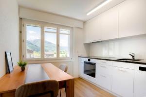 a kitchen with white cabinets and a table with chairs at Casa Olympia in Andermatt