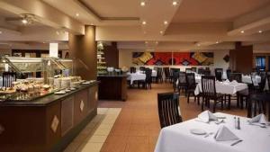 a restaurant with white tables and chairs and a buffet at Avenue Alhambra princess resort in Hurghada