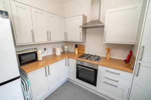 a kitchen with white cabinets and a microwave at Family & Group Stay – 5-Bed Home, Parking in Swansea