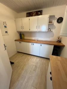 a kitchen with white cabinets and a wooden floor at Sérénité Marais-Océan in Longeville-sur-Mer