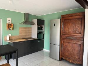 a kitchen with a white refrigerator and a wooden door at Sérénité Marais-Océan in Longeville-sur-Mer