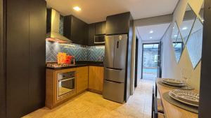 a kitchen with a stainless steel refrigerator and a table at Chalé 662 estilo e conforto a 7 min do centro in Petrópolis