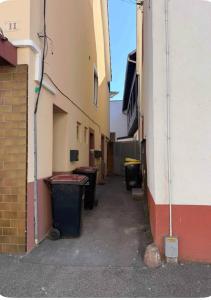an alley between two buildings with trash cans at F2 Neuf Luxe Centre Haguenau Parking Gratuit in Haguenau