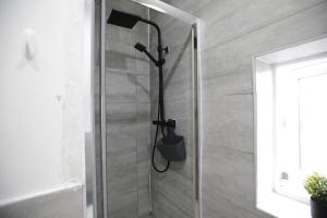 a shower with a black shower head in a bathroom at Dixon House, Sleeps 6, Free Parking, Long or Short Stays - by NMB Property in Horwich