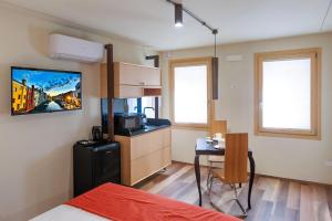a room with a bed and a table and a kitchen at LE RIVE Guest House La Ciosà in Chioggia
