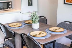 a wooden table with chairs and plates and a plant at The Hideaway With AC in London +10 photos