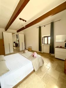 una camera da letto con un grande letto bianco con due cuscini rosa di Nidadi Trulli d'Itria a Martina Franca