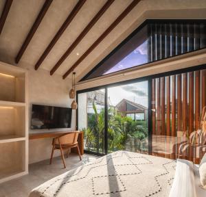 a bedroom with a large window and a bed and a tv at Blacksand Villas Bingin, Uluwatu by Sandara in Uluwatu