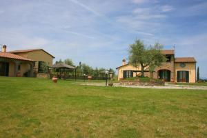 une maison avec une cour verdoyante devant elle dans l'établissement Podere Marcigliano, à Cortone