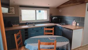 a small kitchen with a table and chairs and a sink at Gite bleu in Aizenay