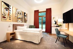 a bedroom with a bed and a desk and a television at Kim Schlosshotel im Park in Dresden