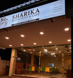uma placa para um restaurante e café sharma com cadeiras em sharika cafe home stay em Auroville
